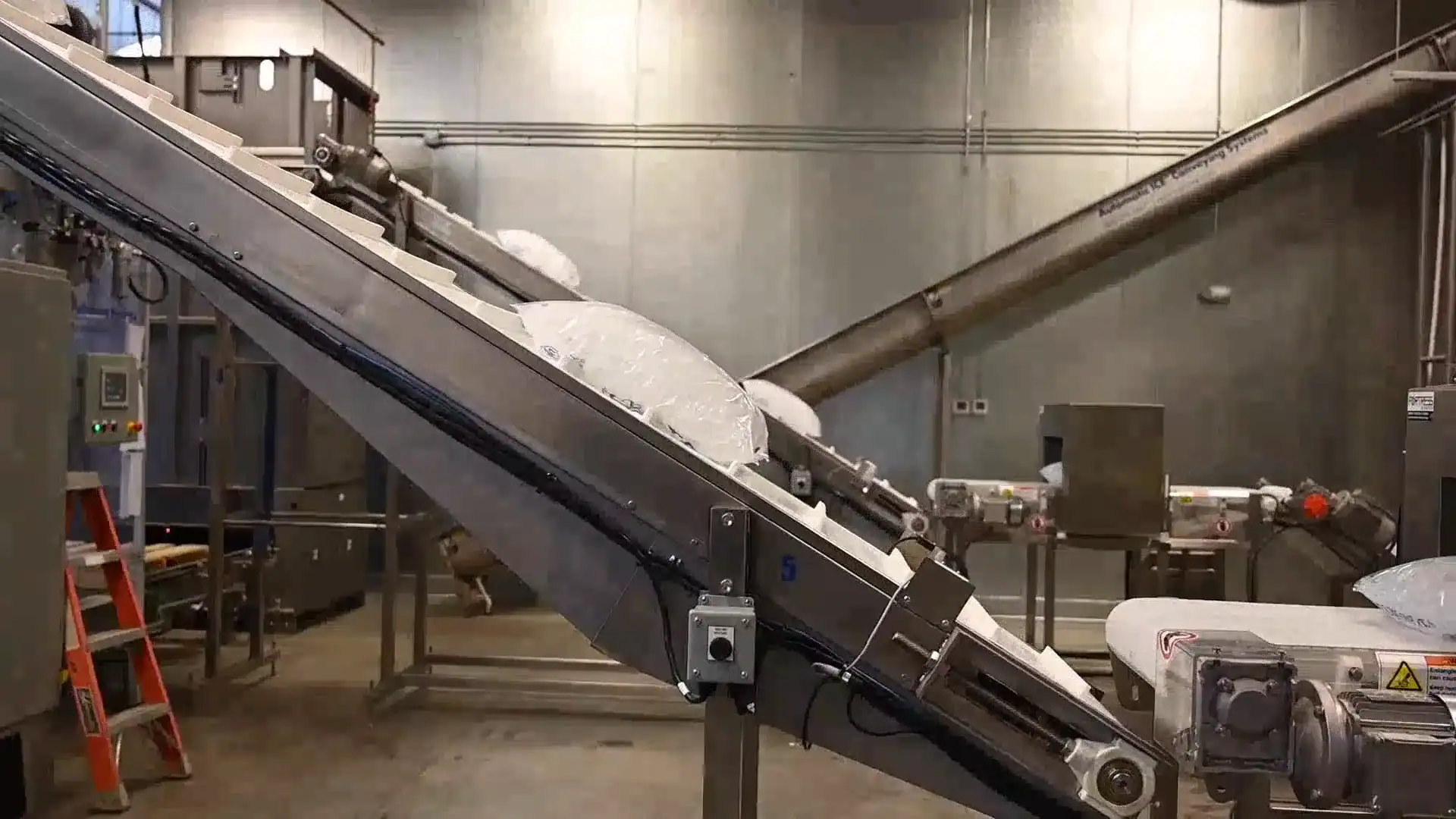 Sealed bags of food-grade ice moving along an automated conveyor line inside the Supreme Ice production facility